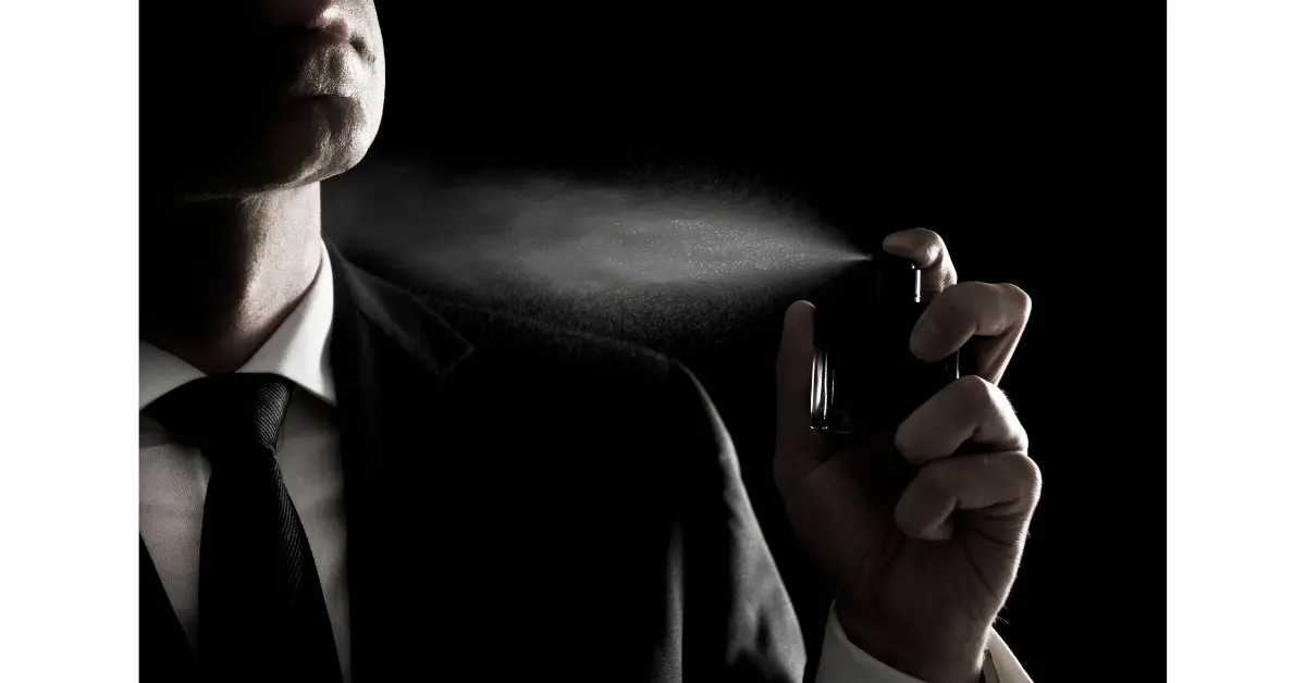 The picture shows a man spraying perfume at his neck and collar