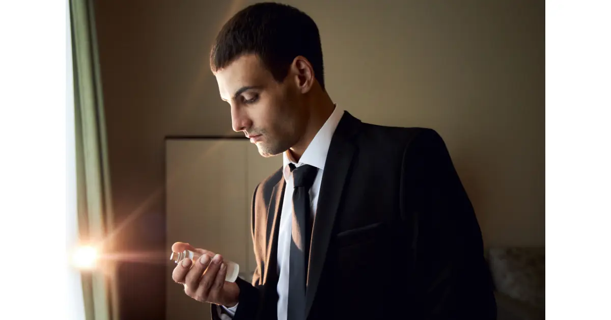 A man is shown in the picture who is watching his perfume which is smell like alcohol because it is about to expire