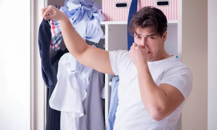 a man holding his stinking socks which is taken out from closet and his holding his nose in disgust