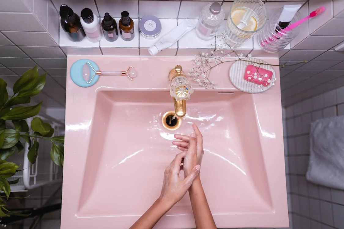 Rubbing and washing hands with soap in the pink sink